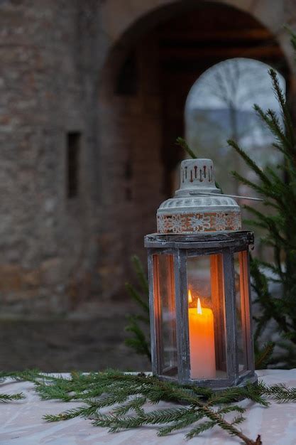 Premium Photo A Burning Candle In A Christmas Lantern Against The