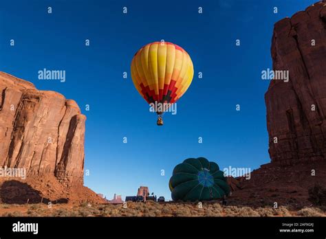 A Hot Air Balloon Rises In The Early Morning Sky In The Monument Valley