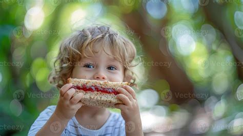 A young child eating a sandwich in the woods 51266190 Stock Photo at