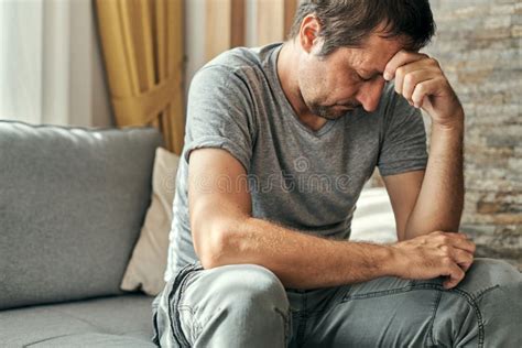 Depressed Sulking Man Sitting Alone At Living Room Sofa And Thinking