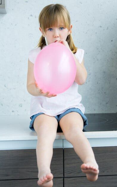 Mignon Petite Fille Gonflant Un Ballon Rose Dans La Cuisine Photo