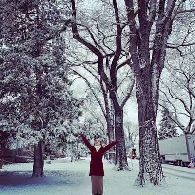 a woman is standing in the snow with her arms up and hands raised above her head