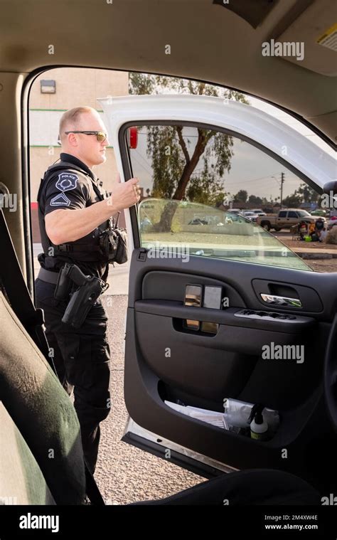 White Male Police Officer Getting Out Of Vehicle To Investigate A