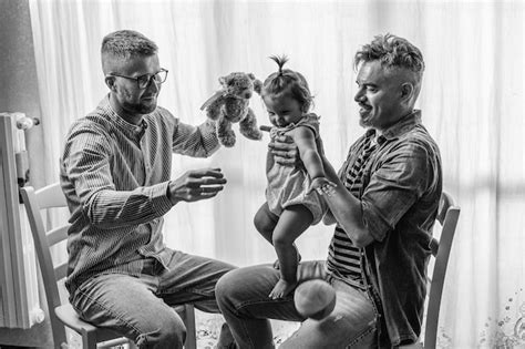 Casal Gay Masculino Menina Adotada Em Casa Dois Pais Bonitos Brincando Sua Filha Foto