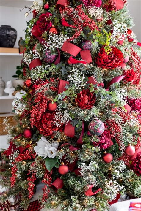 A Christmas Tree Decorated With Red And White Flowers