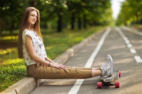 坐在公园的时髦年轻愉快的妇女在longboard和微笑投入了他的脚 溜冰板运动 生活方式 库存照片 图片 包括有 夫人 愉快 74255382