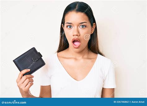 Jovencita Y Bella Latina Sosteniendo Una Billetera De Cuero Asustada Y Asombrada Con La Boca