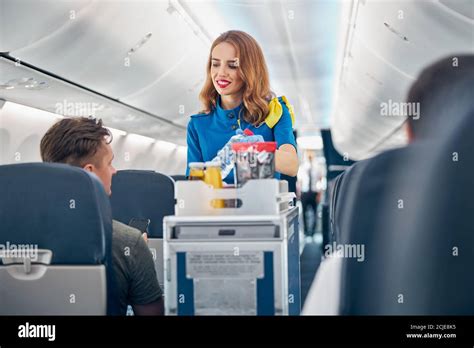 Flight Attendant Serving Food And Drinks To Passengers On Board Stock