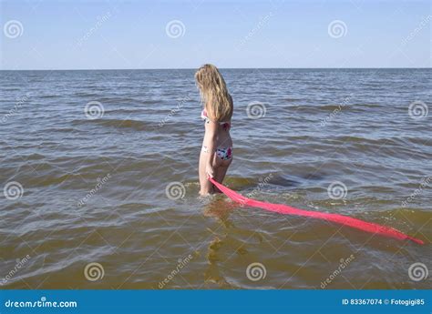 Ragazza Bionda In Un Bikini Che Sta Sulla Spiaggia E Che Tiene Un