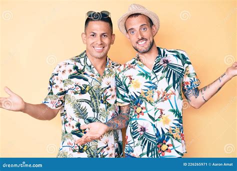La Pareja Joven Gay De Dos Hombres Con Sombrero De Verano Y Camisa Hawaiana Sonriendo Mostrando