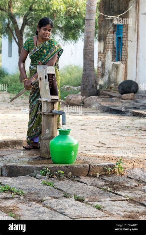 Indian Woman Filling Plastic Water Pot From A Rural Village Hand Pump