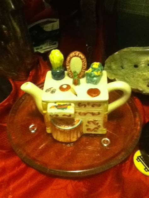 There Is A Miniature Tea Pot On Top Of A Glass Plate With Other Items