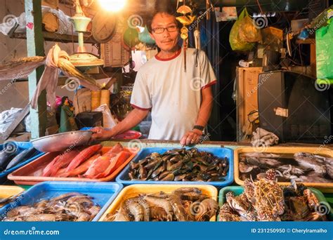 A Male Fishmonger Selling Freshly Caught Seafood And The Local Market