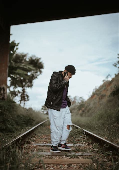 Pria Berjaket Hitam Memegang Asap Merah Di Jembatan Metal · Foto Stok