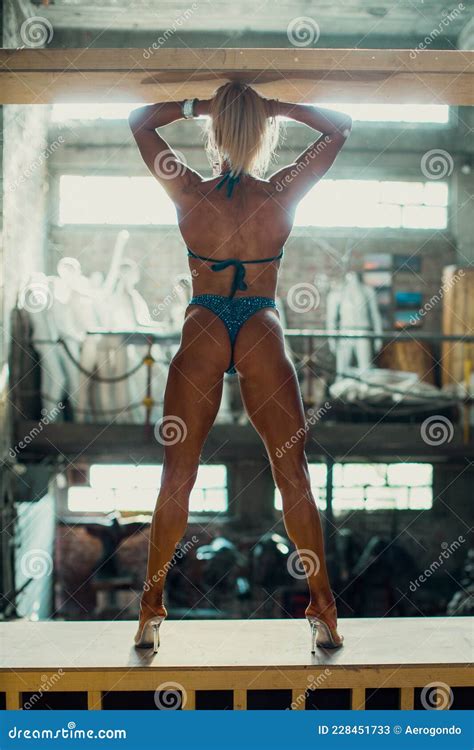 Blonde Muscular Female Bikini Fitness Champion Posing In Abandoned Storage Space Stock Image