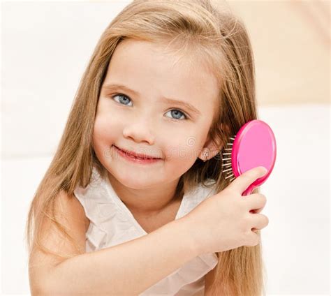 Portrait De La Petite Fille De Sourire Se Brossant Les Cheveux Photo