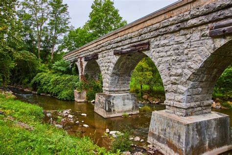 Old Stone Arch Bridge For Train Tracks Over Small River Stock Photo