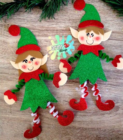 Two Christmas Elfs Made Out Of Felt On A Wooden Table With Pine