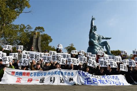 平和公園での座り込みで「平和」と書かれたカードを掲げる被爆者や高校生たち 「ウクライナに平穏を」 長崎で被爆者ら65人が正月座り込み