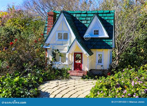 A Miniature Yellow House with a Green Roof and a Red Door in the Garden ...