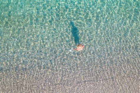 Vista Superior Joven Hermosa Mujer Desnuda En Un Sombrero Sacando Bikini En Agua De Mar Foto