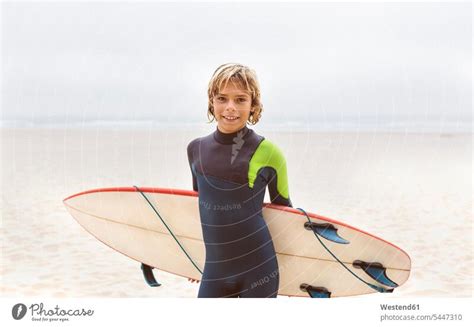 Spain Aviles Portrait Of Smiling Young Surfer Carrying Surfboard On