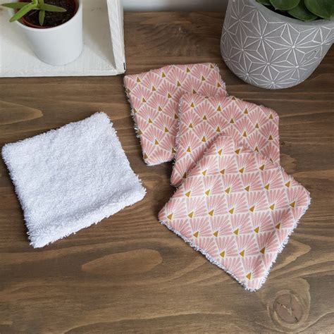 Three Pink And White Towels Sitting On Top Of A Wooden Table Next To A