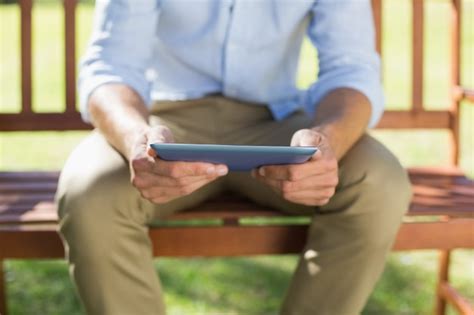 Homem Sentado No Banco Do Parque Usando O Tablet Foto Premium