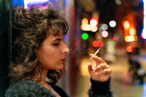 Mujer Latina Fumando Con Un Cigarrillo En La Mano En La Calle Por La Noche Foto De Archivo