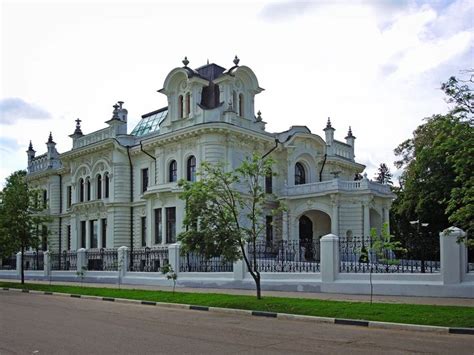 a large white building sitting on the side of a road next to a lush ...
