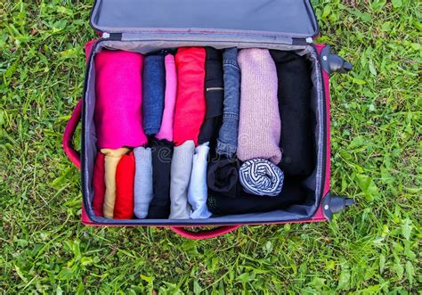 Open Suitcase on the Green Grass with Different Clothes Folded ...