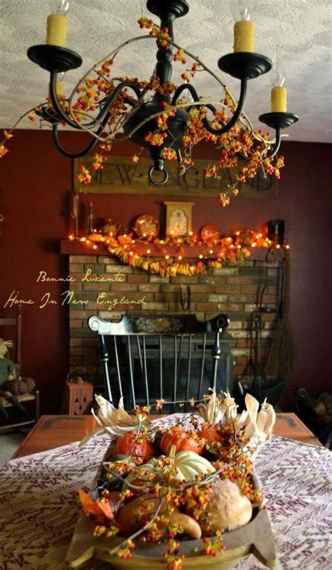 A Chandelier Hanging Over A Dining Room Table With Pumpkins And Gourds