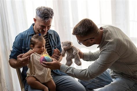 Pareja gay masculina con una niña adoptada en casa dos padres guapos jugando con su hija familia