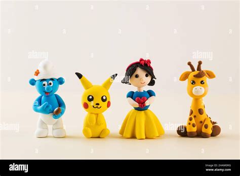 Toy figures of cartoon characters made of polymer clay on light beige ...