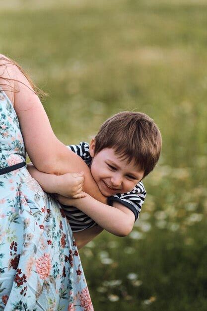 La Jeune Mère Serre Son Fils Dans Ses Bras Et Il Rit Avec Plaisir Et Embarras Photo Premium