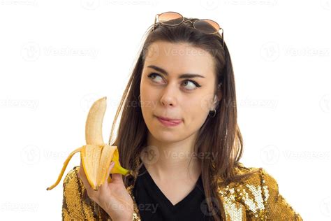Brunette Woman In Golden Jacket Eating A Banana Stock Photo At Vecteezy