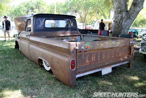 An Old Pick Up Truck Is Parked In The Grass With People Standing Around