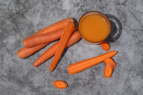 Vaso de jugo de zanahoria fresco sobre fondo de hormigón gris con