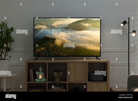 Modern TV set on wooden stand in room. Scene of nature themed movie on ...