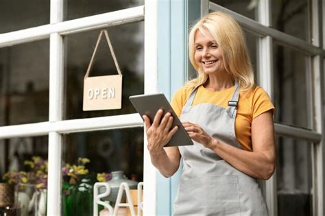 Premium Photo Mature Woman Using Digital Tablet While Standing At Terrace Near Her Cafe