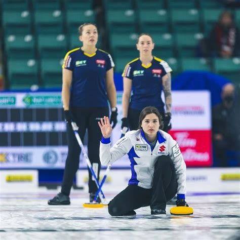 curling team members on the ice waiting for their turn to play in an ...