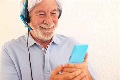 Senior White Haired Man With Headphones Standing Against White