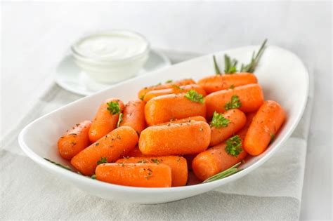 Premium Photo | Small baby carrots in white soup plate on table