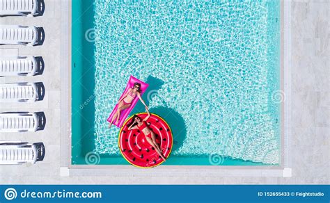 Twee Sexy Meisjes In Bikini Zwemmen In Een Zwembad Op Opblaasbare Matrassen Stock Afbeelding