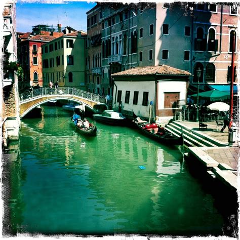 people are riding boats down the canal in venice, italy on a sunny day with green water