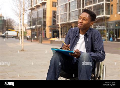 Wheelchair Bound Man Looking Thoughtful With Folders And A Pen Stock