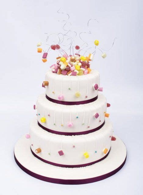 A Three Layer Cake With Sprinkles And Candies On The Top Tier