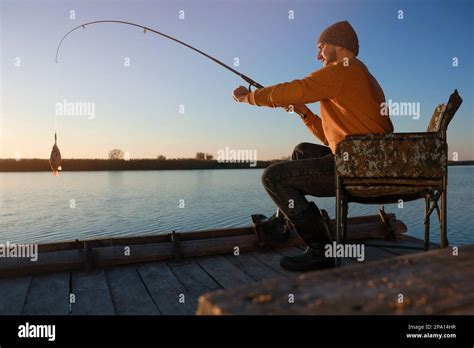 Fisherman Catching Fish With Rod At Riverside Stock Photo Alamy