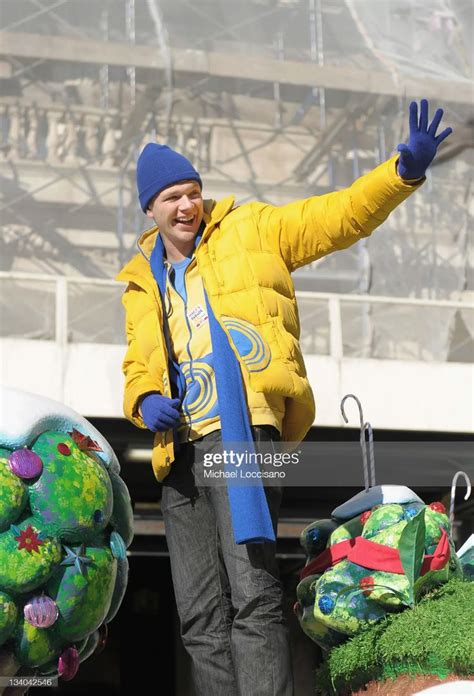 a man in yellow jacket and blue hat waving