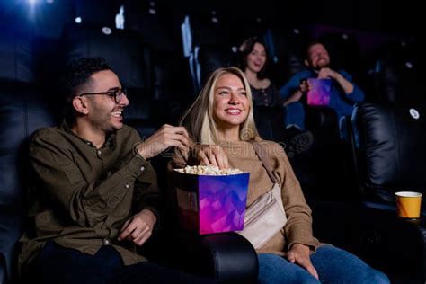 Cheerful Young Intercultural Couple Eating Popcorn While Sitting In